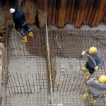Bauarbeiter verteilen den Frischbeton für das Fundament der Ufermauer.